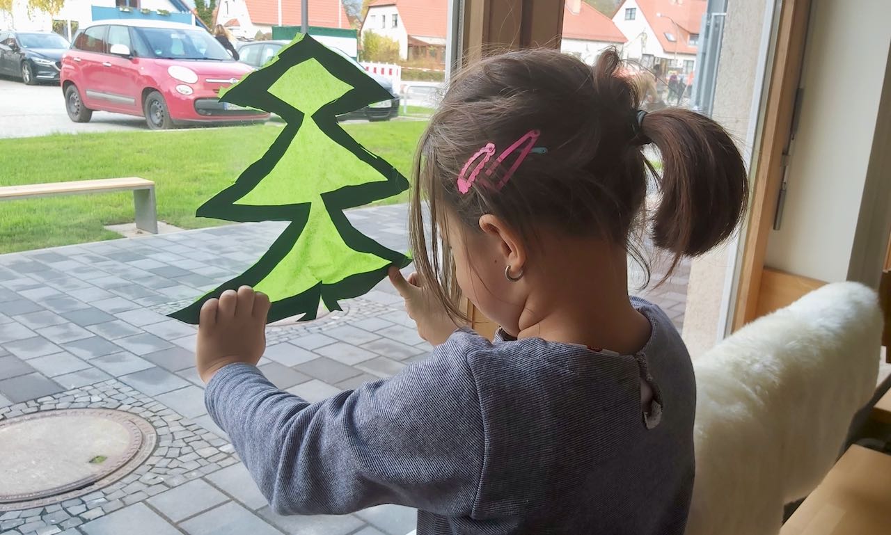 Merle hängt im Familienzentrum den ersten fertigen Fensterschmuck auf. | Foto: Caritas Südniedersachsen