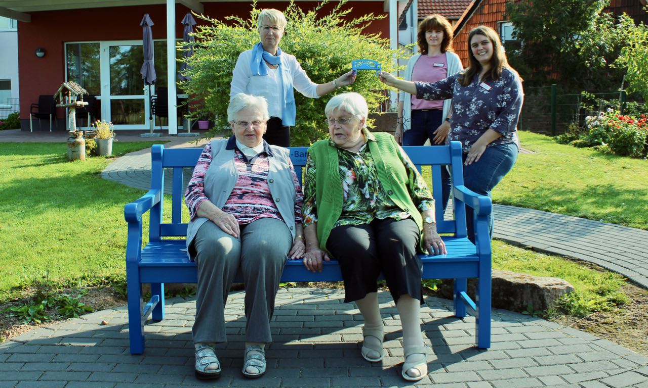 Neues Sitzmöbel für den Garten der Caritas-Tagespflege St. Vinzenz: die Geschwister Antonia Knöchelmann und Walburga Ring ruhen sich gleich nach dem Aufstellen der Bank aus. Sabine Gebhardt übergibt die Miniaturbank an Ute Schimanski, und Melanie Petroschka von der Caritas (v.l.). | Foto: Nicole Hammer / VR-Bank Mitte eG