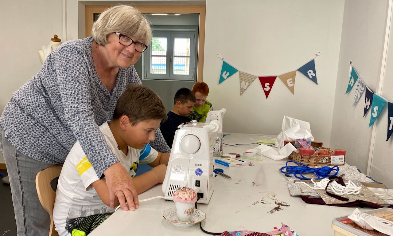 Bärbel Schneegans zeigt Nico, wie er mit einer Nähmaschine arbeiten kann. | Foto: Isabel Lubojanski / Caritas