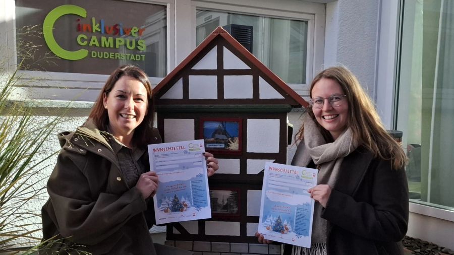 Das Bild zeigt Janine Möller und Emma Fuckner vor dem Fachwerkaus-Briefkasten. Beide halten ein Exemplar des Wunschzettels in ihren Händen.