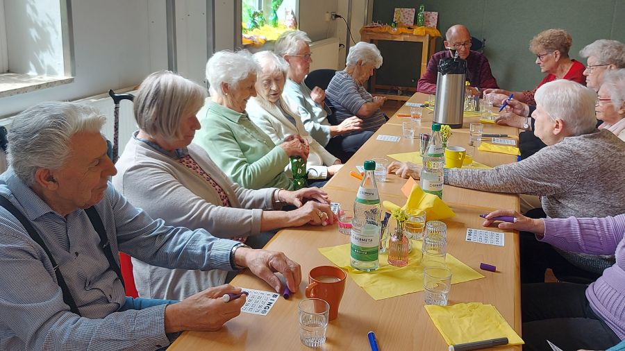 Viele Menschen sitzen an einem langen Tisch und spielen Bingo.