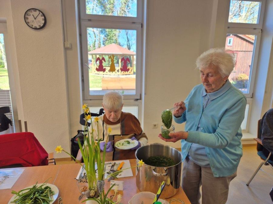 Das Foto zeigt eine Frau, die fertiges Bärlauch-Pesto aus einem großen Topf in ein kleines Glas abfüllt.