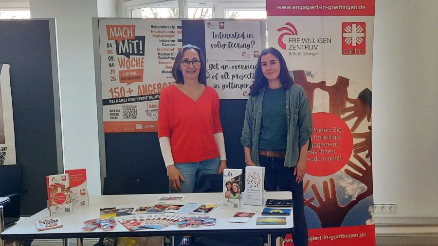 Zwei Personen stehen hinter einem Tisch mit Infomaterial.