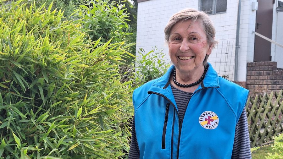 Das Bild zeigt ein Portrait einer Frau in einer blauen Weste der Bahnhofsmission.