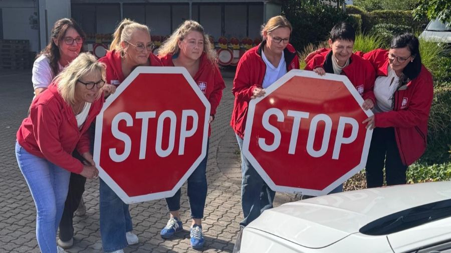 Eine Gruppe Menschen hält Stop-Schilder vor ein Auto.