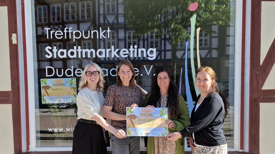 Vier Frauen stehen vor dem Treffpunkt Stadtmarketing und halten das Plakat der Stadtrallye fest.