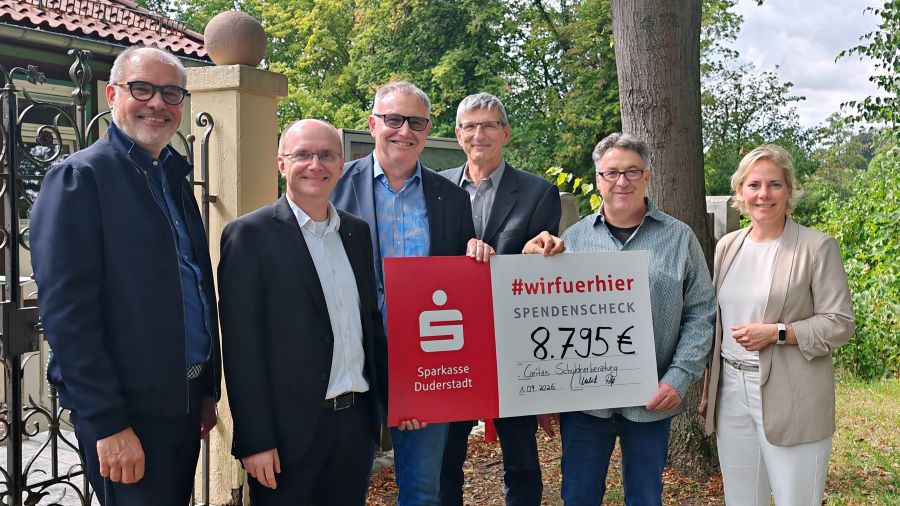 Eine Gruppe Menschen hält einen symbolischen Scheck fest.