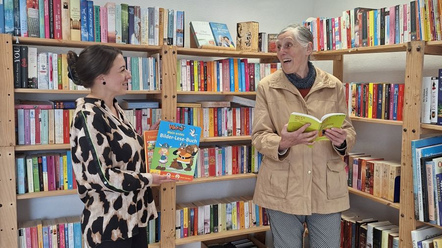 Das Foto zeigt zwei Frauen vor einem Bücherregal.