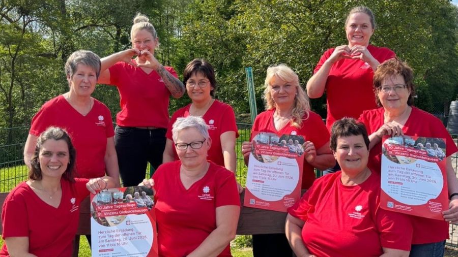 Das Foto zeigt eine Gruppe Frauen in roten T-Shirts, einige halten das Veranstaltungsplakat, einige formen ein Herz mit ihren Händen. 