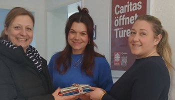 Das Foto zeigt drei Personen bei der Postübergabe.