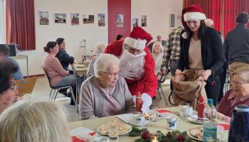 Das Foto zeigt, wie eine als Nikolaus verkleidete Person Geschenke verteilt.