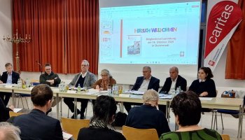 Das Bild zeigt Mitglieder des Caritasrats und des Vorstandsteams, wie sie gemeinsam der Mitgliederversammlung vorsitzen.