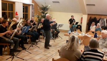 Das Foto zeigt die Blasmusikanten auf der linken Seite, in der Mitte des Fotos singt Adolf Heckmann.