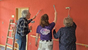 Das Foto zeigt drei Personen mit Pinseln der Wand zugewandt.