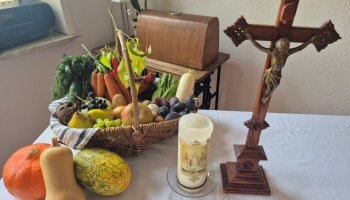 Geschmückter Tisch mit Kürbissen und einem Kreuz. 