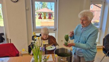 Das Foto zeigt eine Frau, die fertiges Bärlauch-Pesto aus einem großen Topf in ein kleines Glas abfüllt.