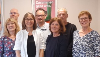 Acht Menschen stehen in einer Gruppe