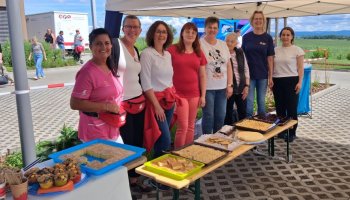 Eine Gruppe steht hinter einer Bank mit zahlreichen selbstgebackenen Kuchen.