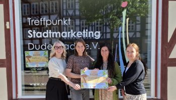 Vier Frauen stehen vor dem Treffpunkt Stadtmarketing und halten das Plakat der Stadtrallye fest.