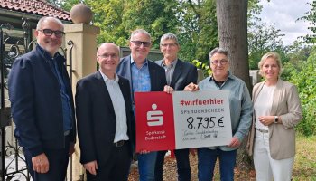 Eine Gruppe Menschen hält einen symbolischen Scheck fest.