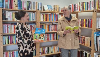 Das Foto zeigt zwei Frauen vor einem Bücherregal.