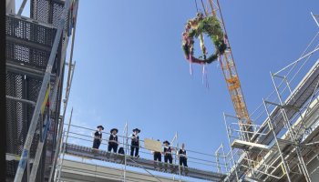 Handwerker stehen oben auf einem Rohbau.