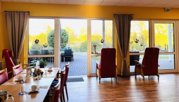 Das Foto zeigt Tische und Stühle sowie einen Blick nach draußen auf die Terrasse.