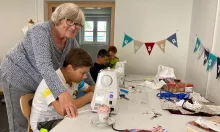 Bärbel Schneegans zeigt Nico, wie er mit einer Nähmaschine arbeiten kann. | Foto: Lubojanski / Caritas