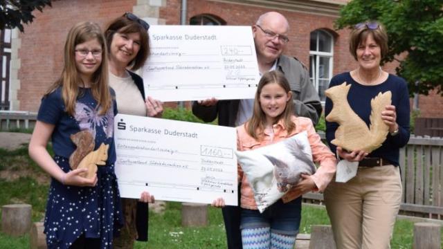 Glücklich über den Erfolg ihrer Spendensammlung überreichen Sonja Engel (l.) und Neele Kolle den Spendenscheck für die Kinder der Eichhörnchen-Gruppe im Inklusiven Campus Duderstadt. Mit dabei waren (v.l.) Lehrerin Gerswit Gödecke und Ortsbürgermeister Klaus Deppener, die den Scheck des Ortsrats hochhalten, sowie Heike Jagemann von der Caritas Südniedersachsen. | Foto: Broermann / cps