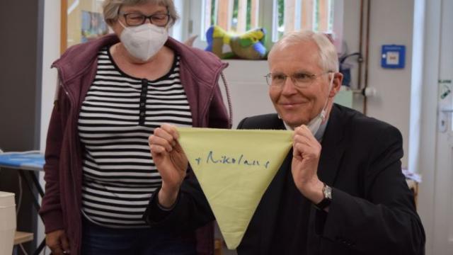 Weihbischof Dr. Nikolaus Schwerdtfeger hält den von ihm genähten und signierten Wimpel hoch. | Foto: Johannes Broermann / cps