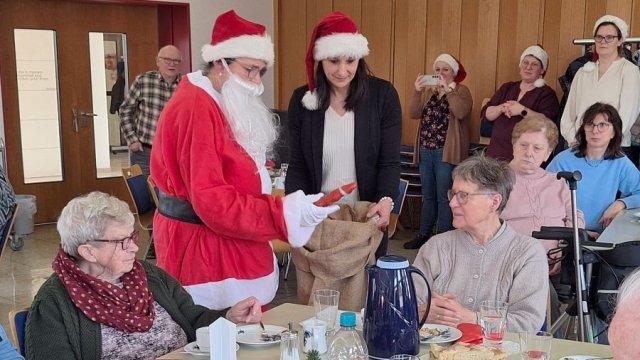 Das Foto zeigt, wie eine als Nikolaus verkleidete Person Geschenke verteilt.