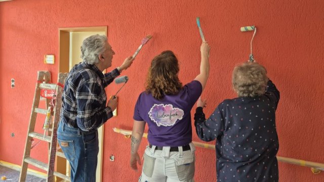 Das Foto zeigt drei Personen mit Pinseln der Wand zugewandt.