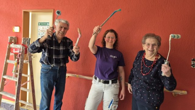 Das Foto zeigt drei Personen mit Pinseln der Kamera zugewandt.