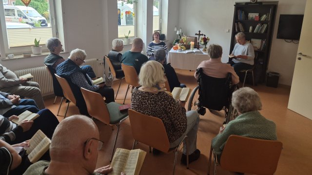 Menschen sitzen zusammen. Halten Gesangbücher in der Hand. 