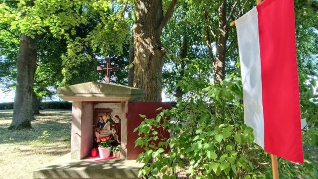 Kreuzwegstation mit rot-weißer Festfahne daneben