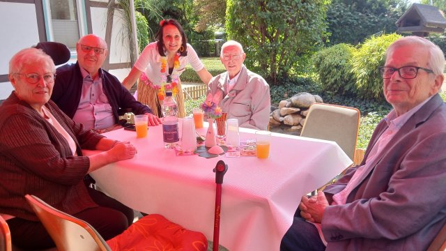 Menschen an einem Tisch. Sie lächeln. 