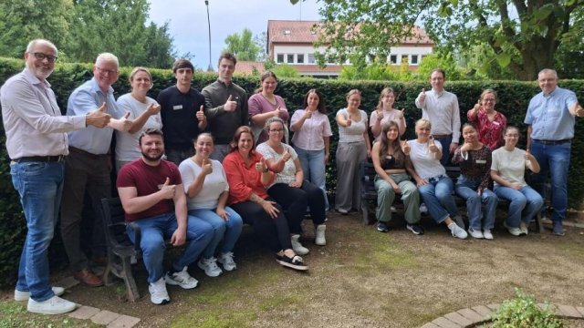Eine Gruppe Menschen ist zum Gruppenfoto versammelt und hält den Daumen in die Höhe.