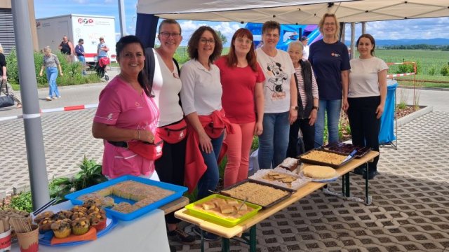 Eine Gruppe steht hinter einer Bank mit zahlreichen selbstgebackenen Kuchen.