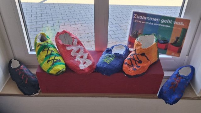 Das Foto zeigt sechs bunt bemalte Gipsschuhe.