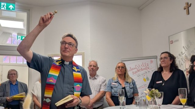 Ein Mann mit Stola hat den rechten Arm erhoben und hält in der Hand ein Aspergill.