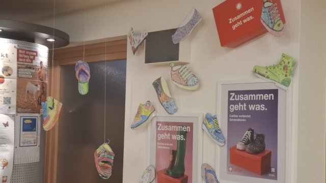 Das Foto zeigt eine Wand mit ausgemalten und ausgeschnittenen Malvorlagen in Schuhform.