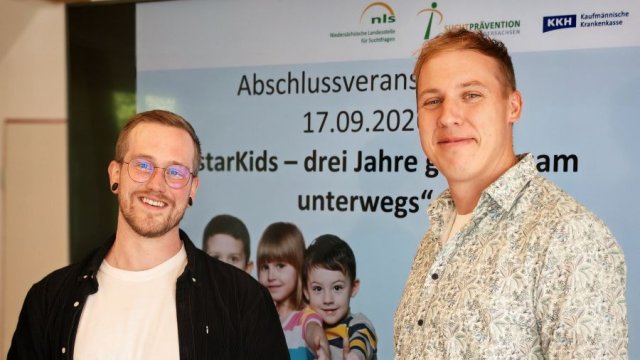 Zwei Personen stehen vor einer Bildschirmpräsentation.