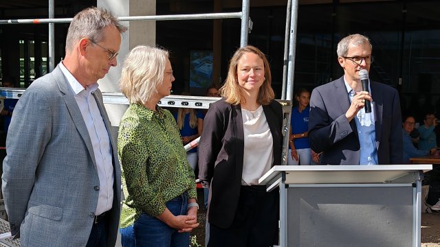 Vier Personen stehen hinter einem Rednerpult.