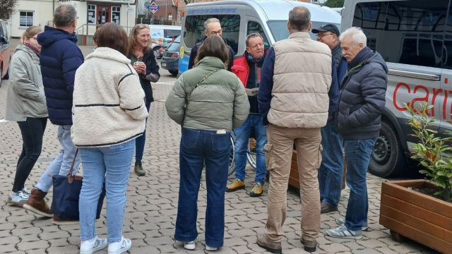 Das Foto zeigt eine Besprechung von stehenden Menschen vor zwei Kleinbussen.