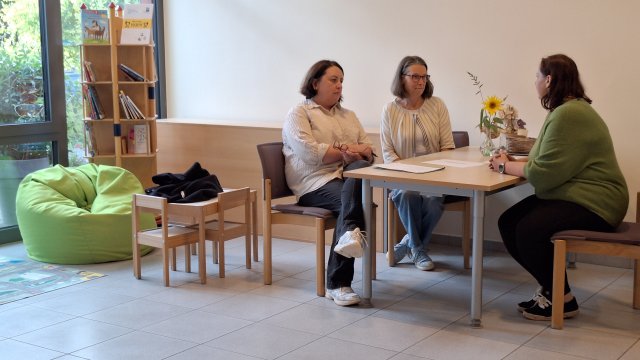 Drei Personen sitzen an einem Tisch