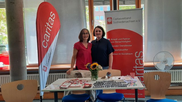 Zwei Frauen neben einer Caritas-Fahne