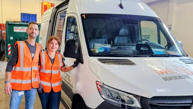 Zwei Menschen mit Warnwesten stehen neben einem Transporter