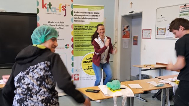 Drei Personen stehen im Klassenraum.