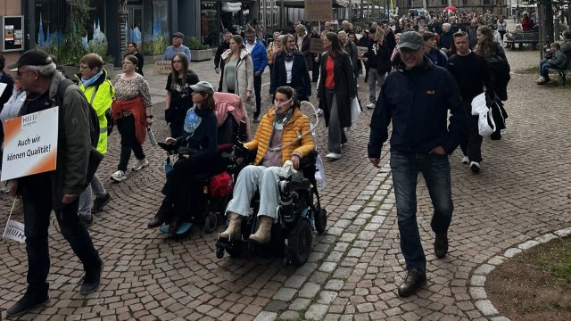 Menschen gehen und fahren in Rollstühlen