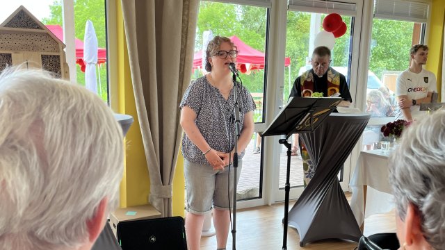 Das Foto zeigt eine Frau, die in ein Mikrofon singt.